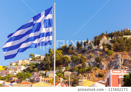 Greek Flag and Hillside Houses in Symi, Greece 115602271