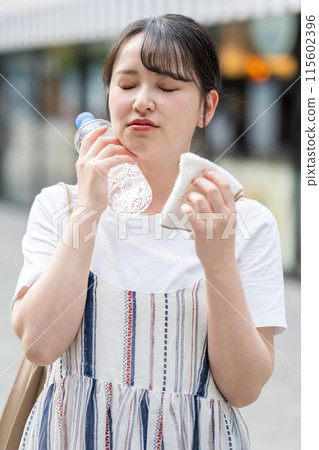 年輕可愛的日本女子在戶外一邊用毛巾擦汗一邊補水|防暑圖片| 年輕可愛的日本女子在戶外一邊用毛巾擦汗一邊補水|防暑圖片| 115602396