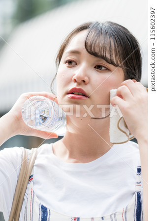 年輕可愛的日本女子在戶外一邊用毛巾擦汗一邊補水|防暑圖片| 年輕可愛的日本女子在戶外一邊用毛巾擦汗一邊補水|防暑圖片| 115602397