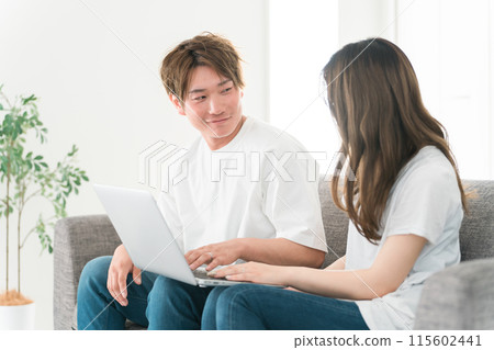 Men and women (couples) using a computer in the living room at home Men and women (couples) using a computer in the living room at home 115602441