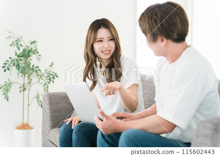 Men and women (couples) using a computer in the living room at home Men and women (couples) using a computer in the living room at home 115602443