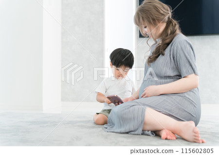 一個男孩看著他的智慧型手機,一個懷孕的母親正在照顧孩子 一個男孩看著他的智慧型手機,一個懷孕的母親正在照顧孩子 115602805