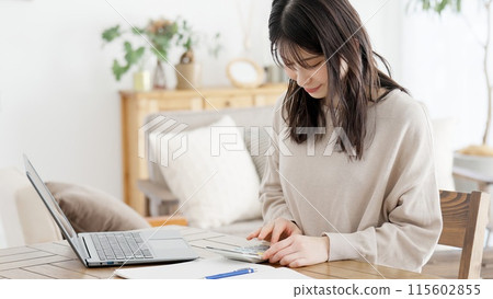A woman calculating expenses with a calculator 115602855