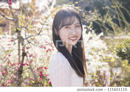 Smiling young woman standing in front of flowers 115603159