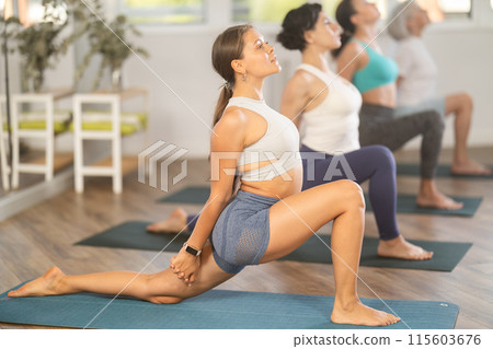 Young girl performing Crescent Moon Pose Anjaneyasana in yoga studio 115603676