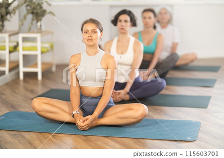 Young woman doing yoga in group in studio Young woman doing yoga in group in studio 115603701