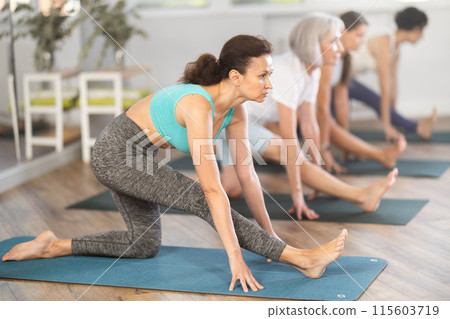 Woman performing Ardha Hanumanasana in group yoga class 115603719