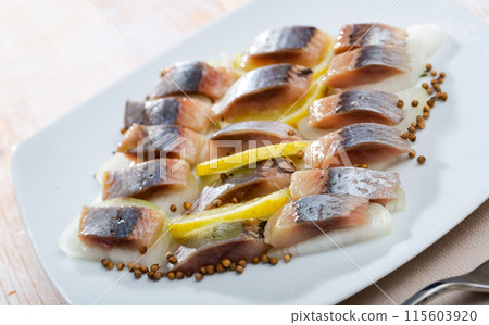 Marinated herring with sliced onion and lemon 115603920