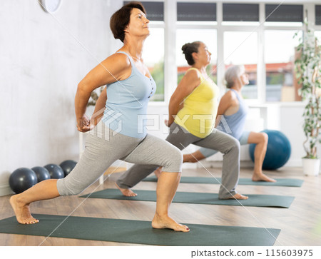 Mature woman stands in warrior pose, Virabhadrasana Mature woman stands in warrior pose, Virabhadrasana 115603975