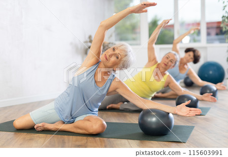 Elderly women perform softball exercises sitting on floor, workout for beautiful figure, toned body 115603991