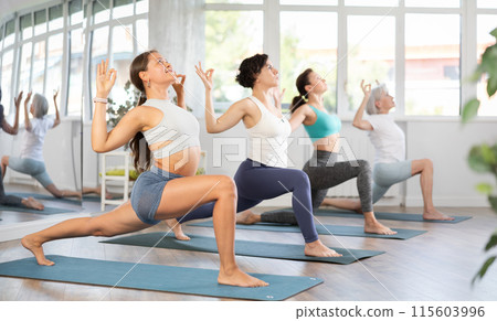 Young female yoga enthusiast performing Virabhadrasana in studio 115603996