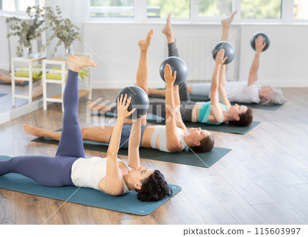 Adult woman doing pilates with soft ball in group 115603997