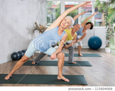 Mature woman performs asana - elongated lateral angle, Parshvakonasana 115604009