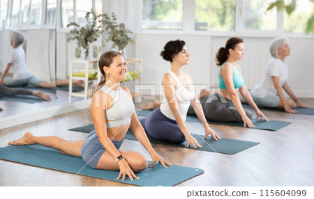 Young woman doing yoga in group in studio Young woman doing yoga in group in studio 115604099