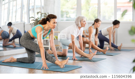 Woman performing Ardha Hanumanasana in group yoga class Woman performing Ardha Hanumanasana in group yoga class 115604396