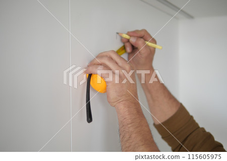 Man measuring wall with a tape measure  115605975