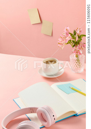 Top-down shot of a pink desk with some essential working items, a morning milk coffee cup and a decorative flower vase placed in a corner. Space on table for showing product 115606091