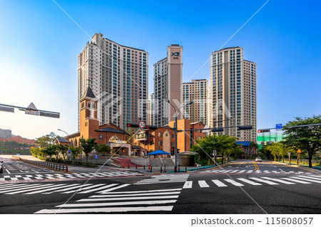 A crosswalk and tranquil traffic conditions at the intersection with a Catholic church reflecting the beautiful evening light. A crosswalk and tranquil traffic conditions at the intersection with a Catholic church reflecting the beautiful evening light. 115608057