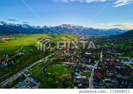 Aerial view of Tatra mountains and Zakopane town at sunset. Panoramic landscape with mountain ranges and green valleys near village. View on Giewont, Poland 115609011