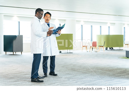 Multinational engineers in white coats talking in the lobby Multinational engineers in white coats talking in the lobby 115610113