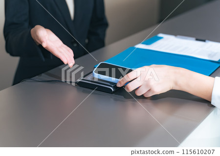 Close-up of a woman's hands paying by touching her smartphone at the cash register Close-up of a woman's hands paying by touching her smartphone at the cash register 115610207
