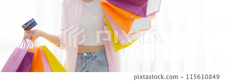 Young asian woman standing holding credit card and paper bag with satisfied. 115610849