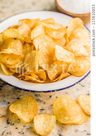 Crispy Potato Chips in bowl on kitchen table. 115610853