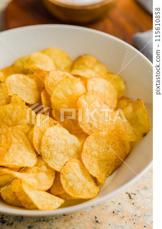 Crispy Potato Chips in bowl on kitchen table. Crispy Potato Chips in bowl on kitchen table. 115610858