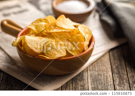 Crispy Potato Chips in bowl on wooden table. 115610873