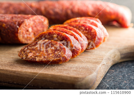 Sliced smoked salami sausage on wooden cutting board. Sliced smoked salami sausage on wooden cutting board. 115610900
