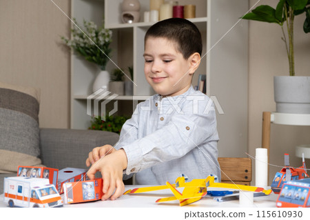 A six-year-old boy glues a paper toy. Creativity and children. 115610930