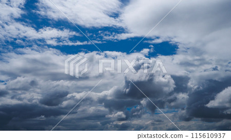 A blue sky with white clouds is adorned with a brilliant shade of blue, adorned with puffy, fluffy white clouds. 115610937