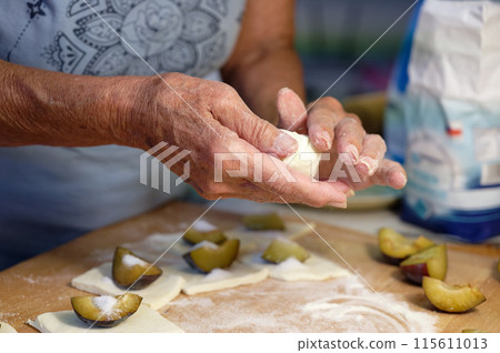Preparation of homemade fruit dumplings with plums. Czech specialty of sweet good food. Dough on kitchen wooden table with hands. Preparation of homemade fruit dumplings with plums. Czech specialty of sweet good food. Dough on kitchen wooden table with hands. 115611013