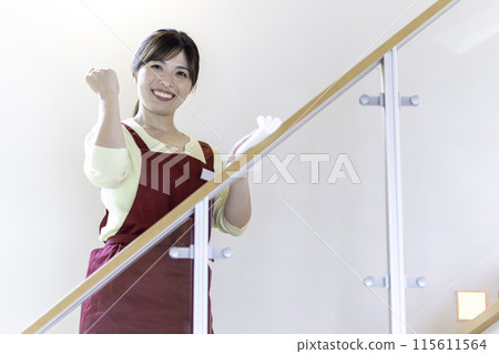 A woman in an apron wiping clean 115611564
