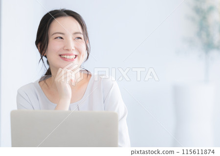 一位操作電腦的年輕女子抬起頭微笑 一位操作電腦的年輕女子抬起頭微笑 115611874