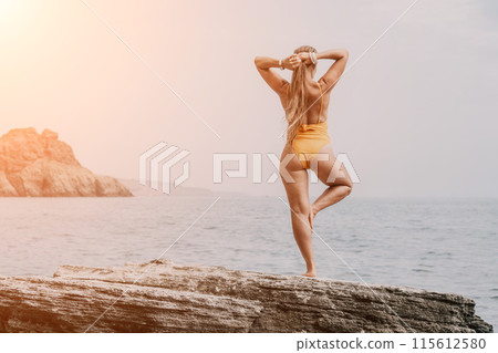 Woman sea yoga. Back view of free calm bliss satisfied woman with long hair standing on top rock with yoga position against of sky by the sea. Healthy lifestyle outdoors in nature, fitness concept. 115612580