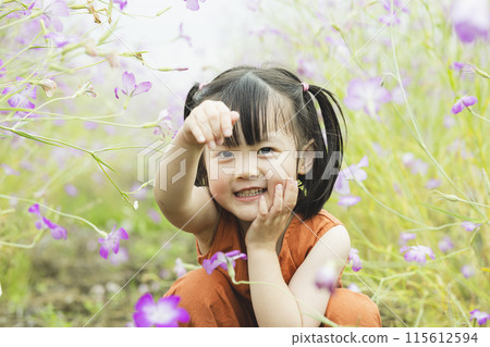 Cute girl playing hide and seek in a flower field 115612594