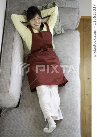 A woman taking a break on the sofa between housework A woman taking a break on the sofa between housework 115613037