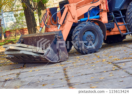 Excavator bulldozer loads old concrete slabs on road repair 115613424