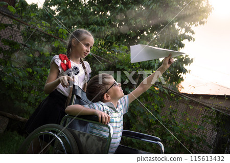 A girl carries a sick boy in a wheelchair A girl carries a sick boy in a wheelchair 115613432