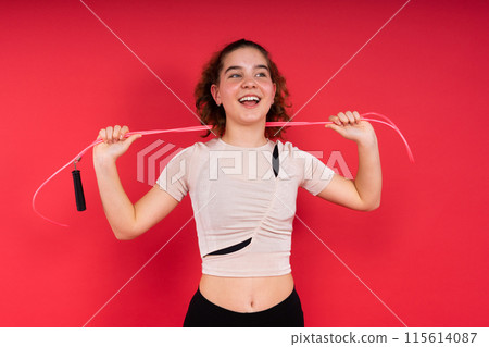 Cute teenage girl with jumping rope looking at camera and smiling while having workout Cute teenage girl with jumping rope looking at camera and smiling while having workout 115614087