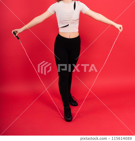 Cute teenage girl with jumping rope looking at camera and smiling while having workout Cute teenage girl with jumping rope looking at camera and smiling while having workout 115614089