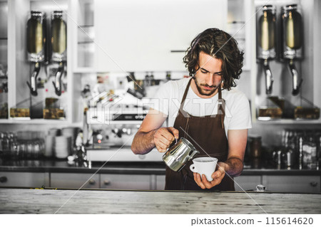 Handsome barista working in coffee shop, preparing coffee. University student working part-time in cafe. Handsome barista working in coffee shop, preparing coffee. University student working part-time in cafe. 115614620