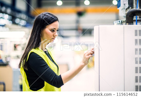 Warehouse employee in warehouse. Female worker in reflective clothing in modern industrial factory, heavy industry, manufactrury. Warehouse employee in warehouse. Female worker in reflective clothing in modern industrial factory, heavy industry, manufactrury. 115614652
