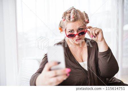 Portrait of beautiful young overweight looking at mirror, having fun. taking selfie with smartphone. 115614751