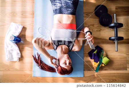 Beautiful redhead woman's home workout routine with dumbbell. Home fitness workout in living room, sporty woman wearing sportswear. 115614842