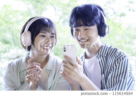 Young couple listening to smartphone music with headphones Young couple listening to smartphone music with headphones 115614884