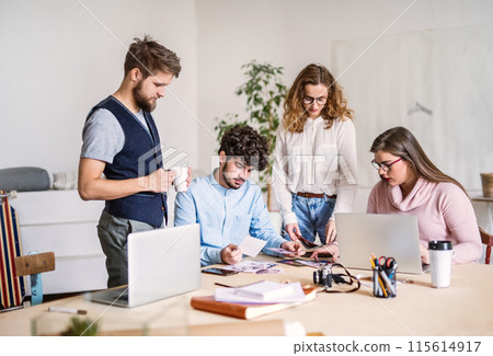 Young group of colleagues working on a new project together in a startup company office. Working in co-working space. Young group of colleagues working on a new project together in a startup company office. Working in co-working space. 115614917