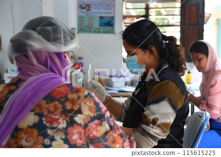 Healthcare worker prepares a vaccine dose for a patient in a clinic 115615225