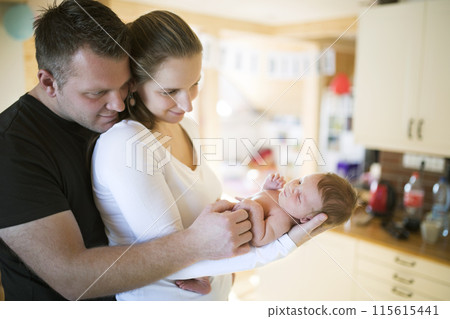 New parents holding newborn baby girl. Unconditional paternal love, idyllic family moment. 115615441